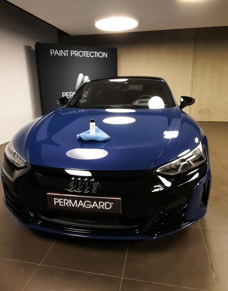 Photo d'un pot de produit Permagard posé sur l'avant d'une voiture bleue